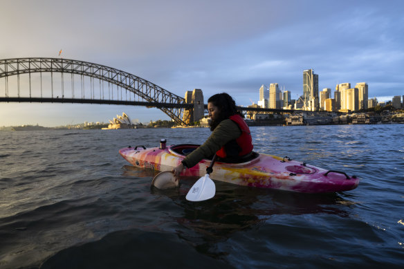 Kayaker Vanesa Moyano picking up rubbish during a Sydney by Kayak tour of Sydney Harbour.