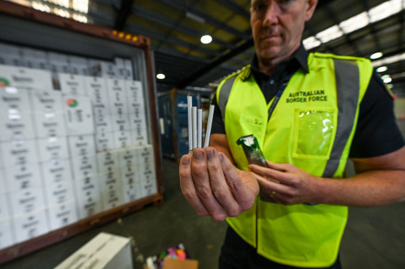 An Australian Border Force officer inspects illegal cigarettes smuggled in a shipping container.