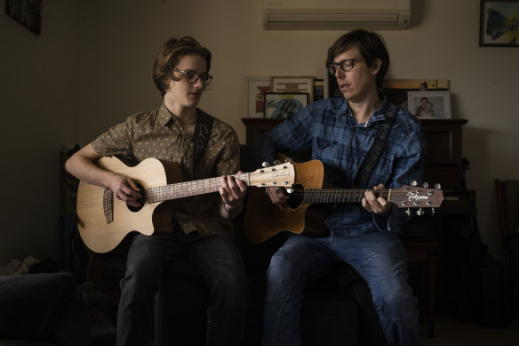 Lucas Cairns with his teenage son Jazziah playing guitar at their home.