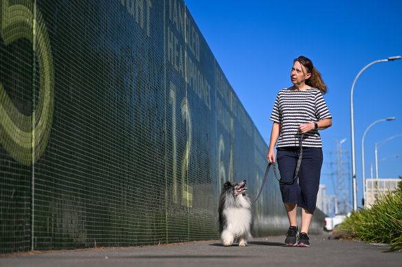 Kensington resident Denise Jury and dog Dougal walk past the Metro Tunnel flood wall in Kensington.