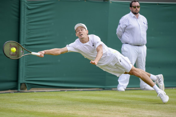 Alex De Minaur reaches to return the ball to Cristian Garin.