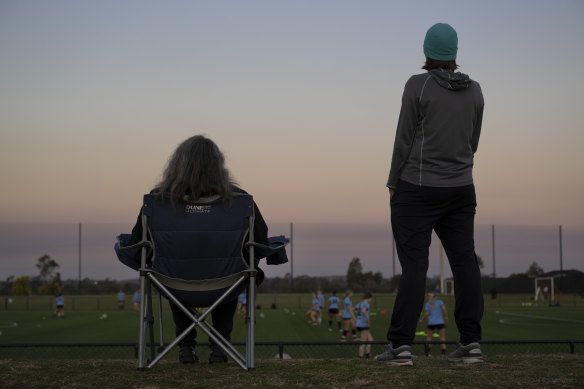 Spectators watch soccer training at North Turramurra Recreation Area from the proposed site of a controversial new grandstand.