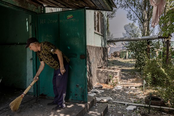 Uma pessoa remove detritos em um prédio de trabalhos de apartamento depois de um minuto antes da bomba russa de deslizar perto de Pokrovsk.
