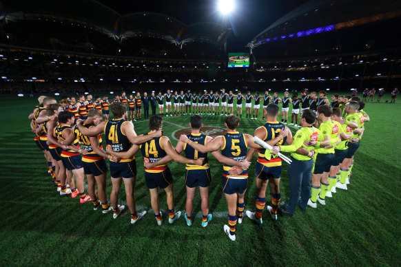 Players from Adelaide and Port Adelaide link arms on Thursday night.