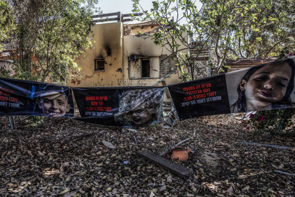 Banners showing members of the Shoham family, who were abducted by Hamas on October 7, outside their damaged home in Kibbutz Be’eri.