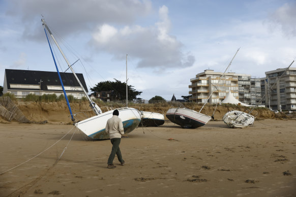 A man walks by boats washed ashore on a breach in Pornichet, in France’s Brittany region.