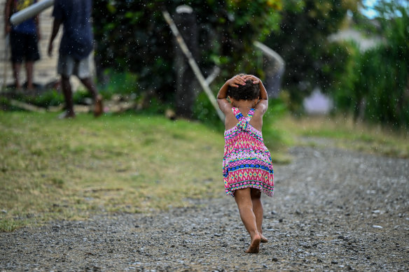 A girl runs away from the rain in Navunisabisabi village in Fiji. 