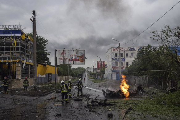 Rescue workers put out the fire of a destroyed car after a Russian attack in a residential area in Kharkiv.