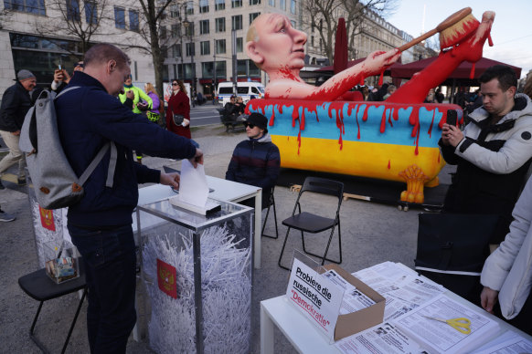 A man casts a ballot in a mock shredder outside the Russian embassy in Berlin.
