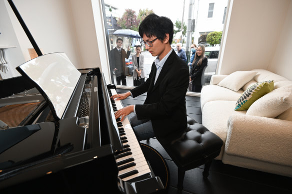 A crowd gathers on the footpath as Emerson Hsu plays a grand piano at the Lindsay Fox-backed Steinway Gallery in Armadale.