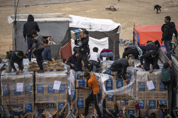 Palestinians climb onto a humanitarian aid truck after it crossed into the Gaza Strip in Rafah.