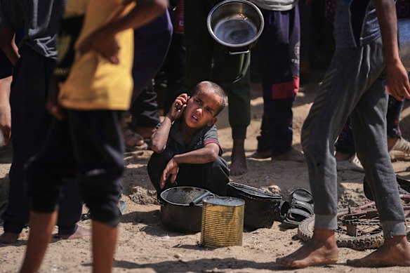 A child rests as crowds jostle for food.