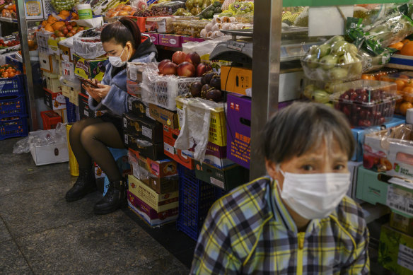 Fruit vendors wear protective masks as they wait for customers at a local market in Beijing.