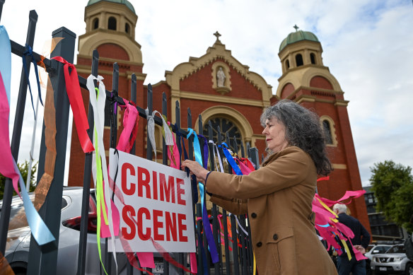 Chrissie Foster and a group of other parents tying ribbons onto the fence of Sacred Heart Church in Oakleigh.