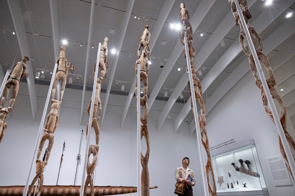 Mexican artist Mark Saldana of Queens looks at Bisj (Ancestor Poles) of West Papua.