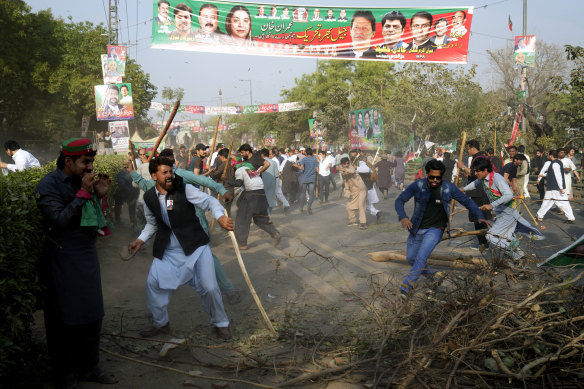Khan supporters throw stones at riot police officers outside his home in Lahore.