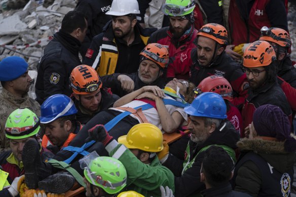 Raziye Kilinc is carried through a crowd on a stretcher after she was rescued under a destroyed building in Iskenderun, southeastern Turkey, on Friday. 