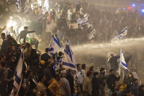 Israeli police use a water cannon to disperse demonstrators blocking a highway.