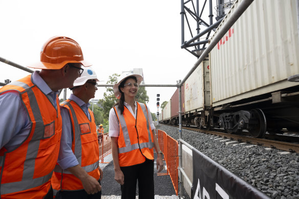 Australian Rail Track Corporation CEO Wayne Johnson, left, Kinsgsford Smith MP Matt Thistlethwaite, and NSW Ports CEO Marika Calfas watch a freight train rumble along the new duplicated rail line.