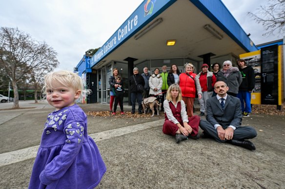 Alex Childs and Dr Aiden Varan (crossed legs) with their daughter Wren and members of West Heidelberg community outside the Olympic Leisure Centre.