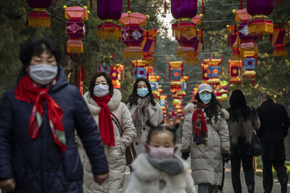 Chinese women and a child all wear protective masks as they walk under decorations in a park after celebrations for the Chinese New Year and Spring Festival were cancelled by authorities on January 25, 2020 in Beijing, China.