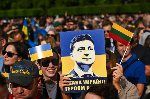 A woman holds a sign with the face of Volodymyr Zelensky at the Raising the Flag for Ukraine event in Vilnius.
