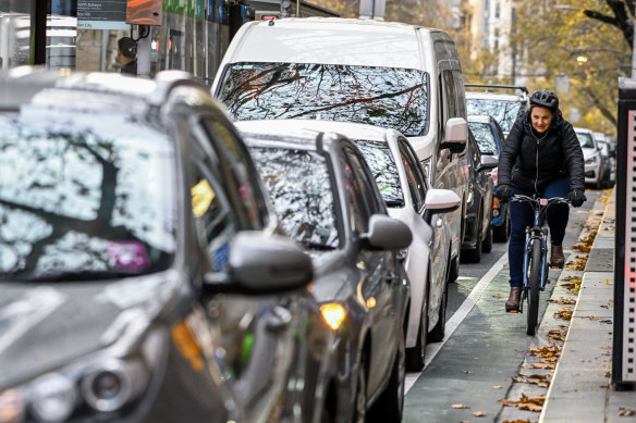 Cyclists make their way along a narrow bike lane along Collins Street. 