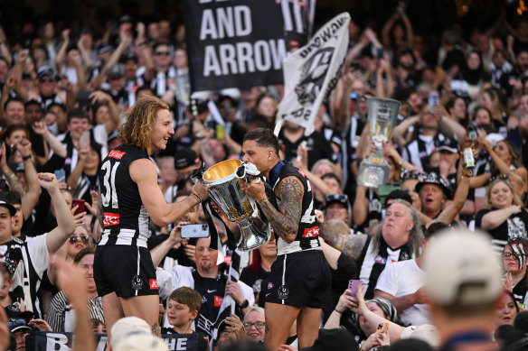 Beau McCreery holds the premiership cup while Bobby Hill kisses it.