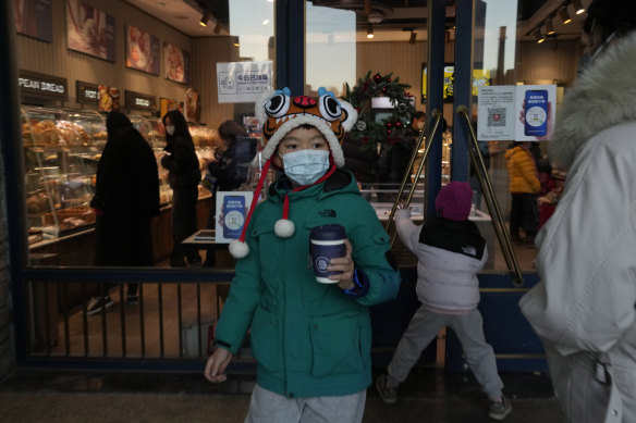 A child walks out with a beverage from a bakery as visitors return to a mall with shops re-opening for business as restrictions are eased in Beijing.