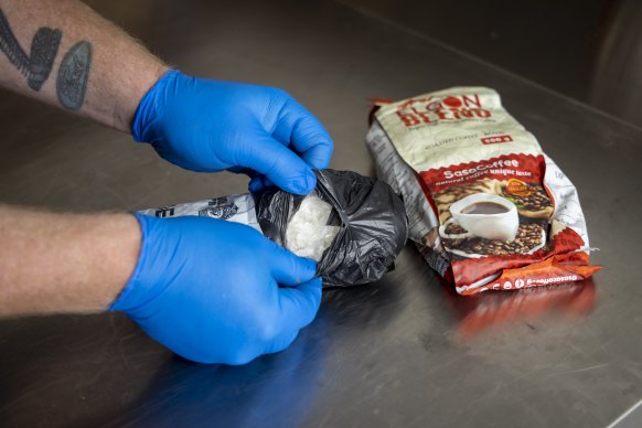 Senior Australian Border Force officer Joel Scantlebury examines a bag full of crystal meth hidden inside coffee packets. 