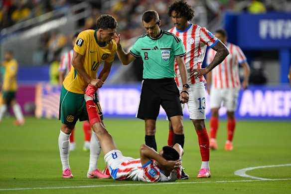 Australia’s Ajdin Hrustic lends a hand to cramping opponent Diego Gomez, of Paraguay.