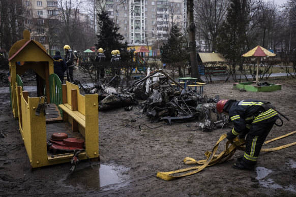 Firemen roll up hoses in front of debris as emergency service workers respond to the helicopter crash on January 18, 2023 in Brovary, Ukraine.