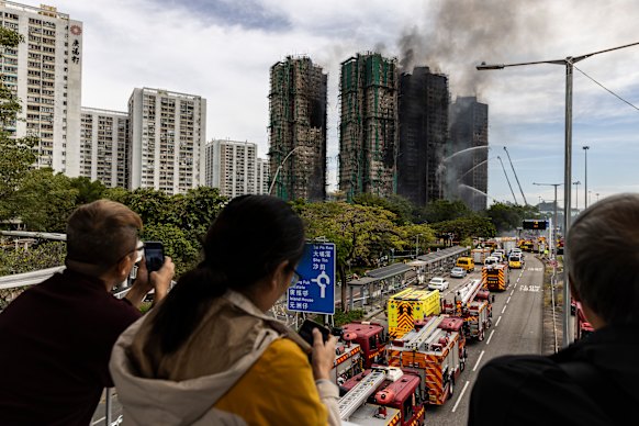 People watch residential buildings that continue to burn at Wang Fuk Court on Thursday afternoon.