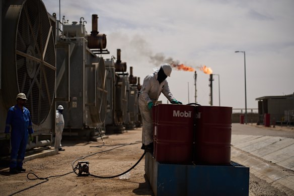 A worker collects engine oil at a degassing station in Zubair oil field in Iraq, whose operations have been reduced due to the war.