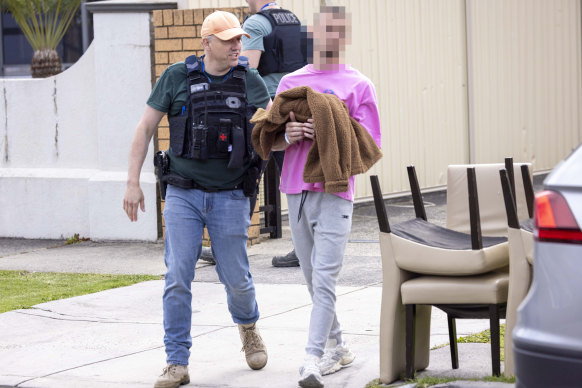 A man is taken from a house by police on Wednesday during raids targeting the Dandenong Thunder soccer club.