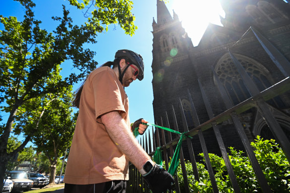 Daniel ties green ribbons on the fence at St Patrick’s Cathedral.