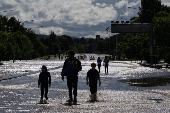 A man in Bathurst crosses floodwaters with children despite being warned by police not to.