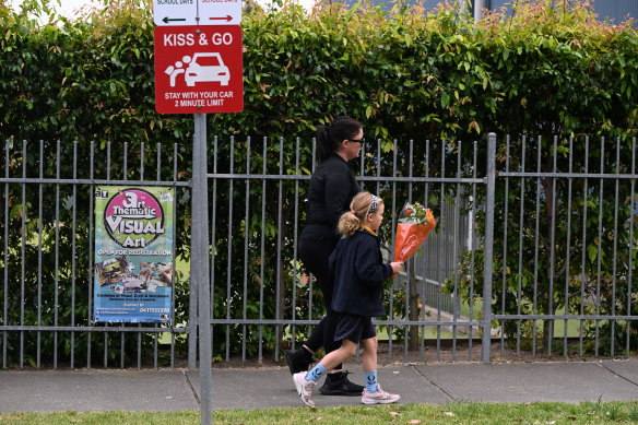 A parent and child bring flowers to Auburn South Primary School alongside the “kiss and go” drop-off lane.