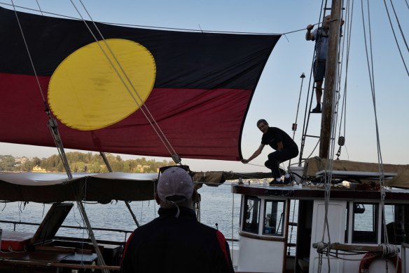 Crew members Craig, Tom and Kel raise the Aboriginal flag after Tribal Warrior docks at Me-Mel.