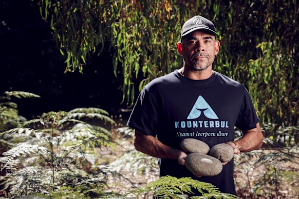 Gunditjmara man Shea Rotumah holding three grinding stones he salvaged from South Road in Kentbruck.