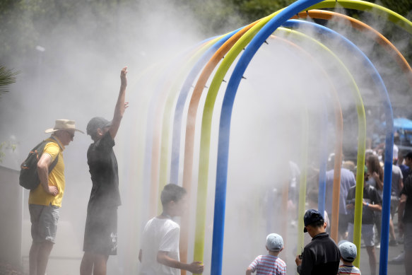 Spectators walk through a water mister as they cool down on the first day at the Australian Open.