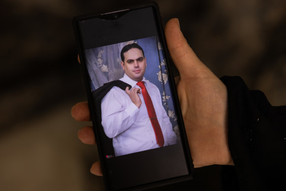 A family member uses her mobile phone to show a photograph of Rajai Sweilem, 39, who was found lying dead with his body full of bullets by his home.