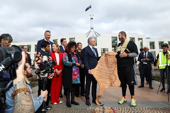 The prime minister is presented with a letter written on kangaroo skin, urging the creation of a truth-telling process for national healing, by First Nations statesman, Travis Lovett.