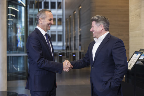 Nine chief executive Mike Sneesby and NRL chief executive Andrew Abdo shake hands in the foyer of the Nine headquarters in North Sydney.