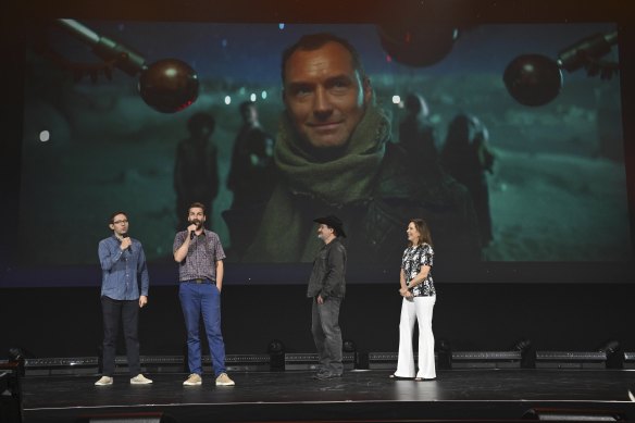Star Wars: Skeleton Crew producers Chris Ford and Jon Watts with Lucasfilm’s Dave Filoni and Kathleen Kennedy in front of an image from Skeleton Crew featuring actor Jude Law.