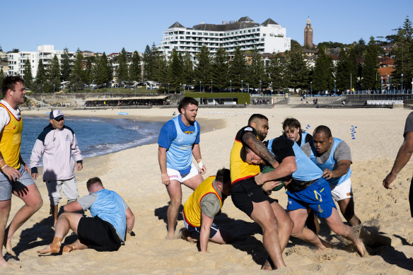 Eddie Jones watches on as Wallabies players doing wrestling and breakdown drills on Coogee Beach.