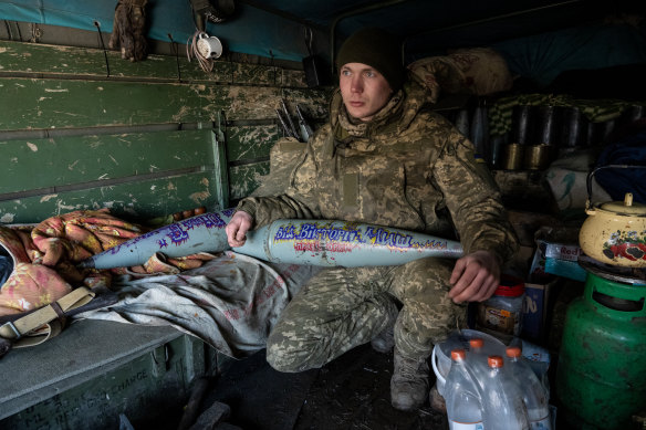 In the southern Donbas region on February 19, a Ukrainian artillery team member holds a captured shell ready to load into a cannon captured from Russian troops in Kherson. 
