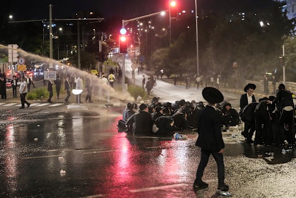 Police use water cannons to disperse ultra-Orthodox Jews blocking a road.