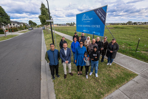 Residents in front of a billboard promising the new shopping centre.