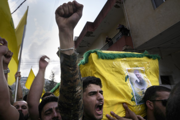 A Hezbollah fighter carries the coffin of his comrade who was killed by Israeli shelling.